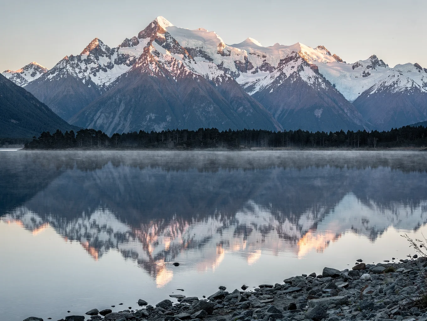 Jagged mountain peaks reflecting in a tranquil alpine lake in New Zealand